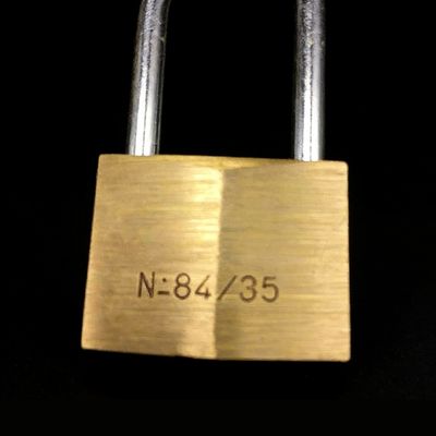 A close-up of a brass padlock with the engraving N-84/35, showcasing sturdy metal construction ideal for home security. Perfect for securing doors, cabinets, or storage units with reliable padlock solutions.