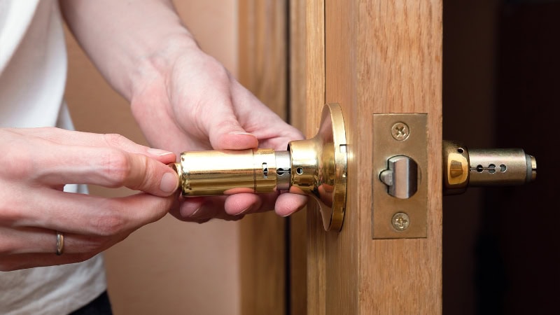 Close-up of a person installing an ANLI LOCK door handle, showcasing the lock's internal components and assembly process.