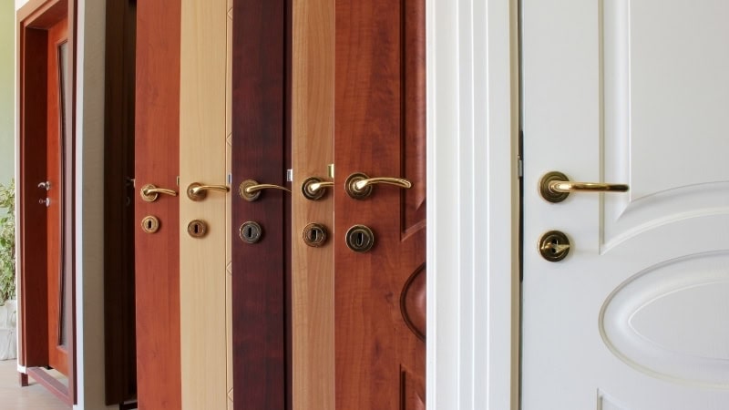 Close-up of various wooden and white door locks and handles, showcasing high-quality ANLI LOCK hardware suitable for residential and commercial doors.