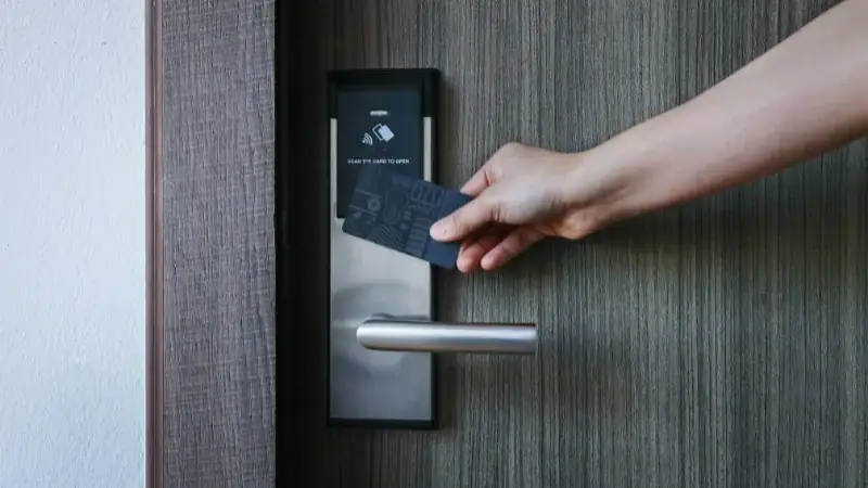 Close-up of a hand using an ANLI LOCK keyless door lock system with a card to unlock a modern door, highlighting smart security technology.