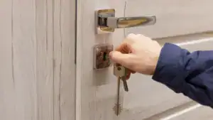 Close-up of a person rekeying a door lock with a key, demonstrating lock rekeying process for enhanced security.