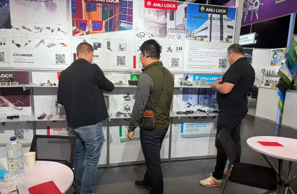Three men examining ANLI LOCK security products at a trade show booth, showcasing various lock solutions and security systems for commercial and residential use.