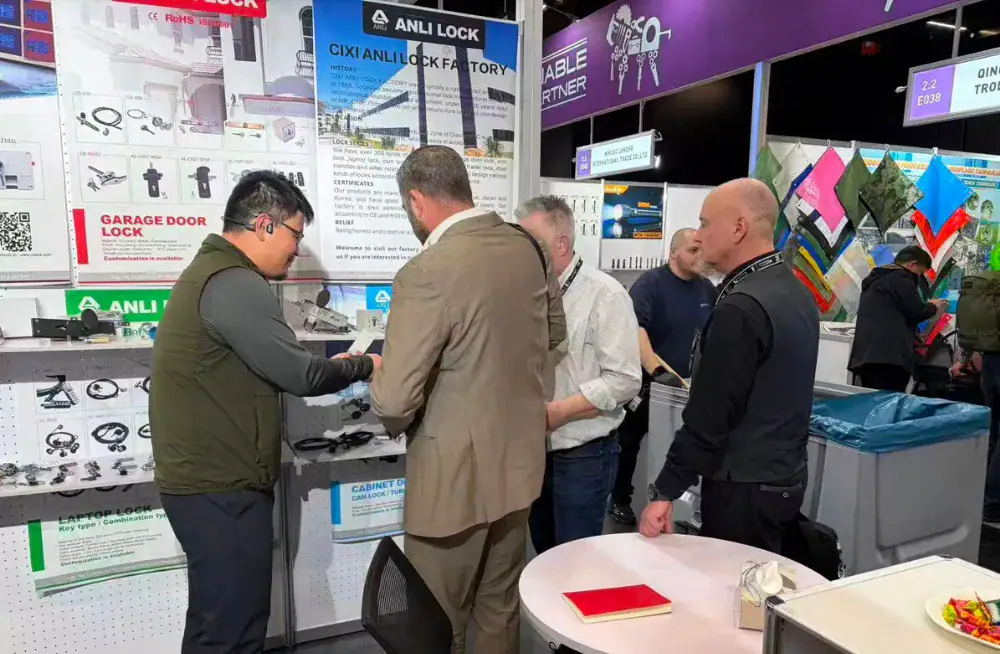 Group of professionals examining ANLI LOCK security products at a trade exhibition booth, showcasing innovative locking solutions for commercial and residential security.