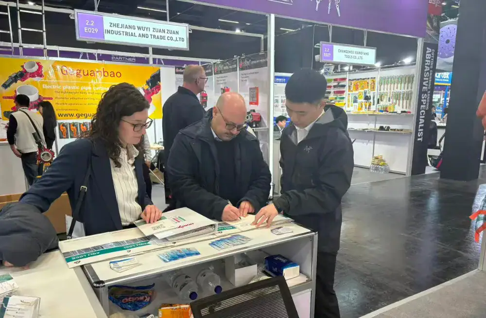 Visitors examining ANLI LOCK products at a trade exhibition booth, showcasing high-security locking solutions with industry professionals discussing features and applications.