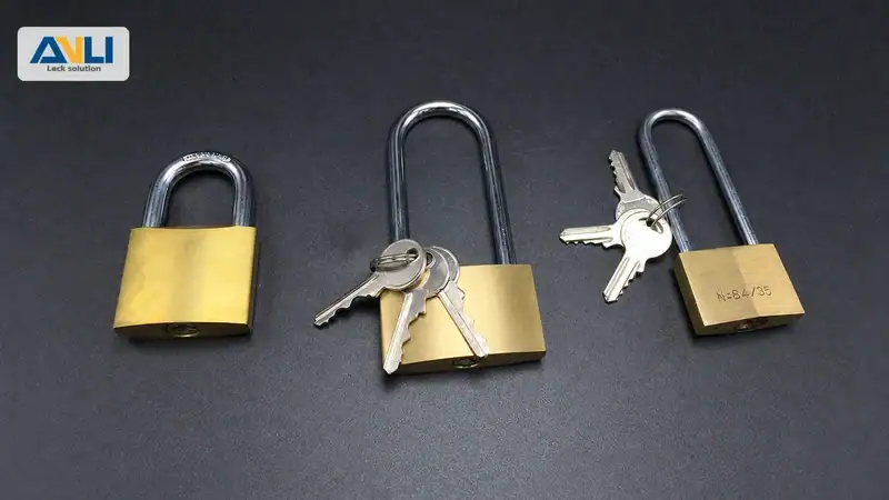 Three brass padlocks of different sizes with keys on a dark background, showcasing the security features of ANLI locks.